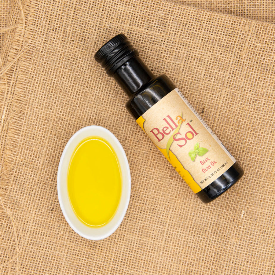 Basil olive oil bottle with yellow oil in a small white dish